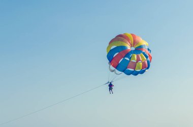 Bir paraşüt ile bir tekne deniz üzerinde uçan bir adam