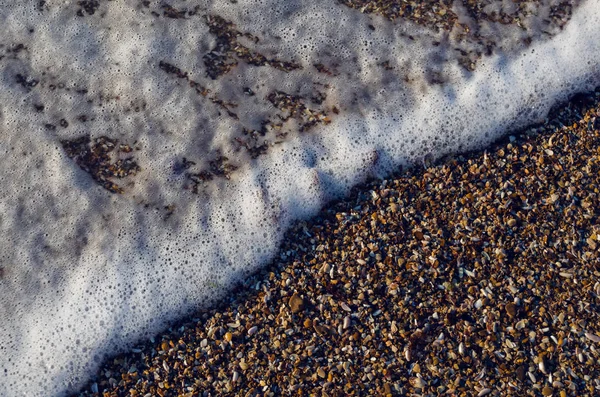 Pobrzeże shellstone z przybrzeżnych fala spieniony — Zdjęcie stockowe