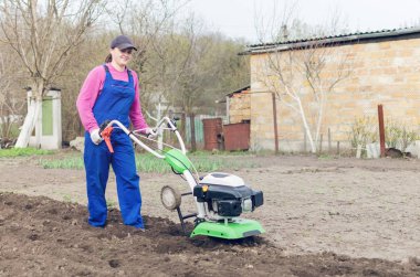 Genç kız bir bahar bahçesinde bir Kültüvatör ile çalışma