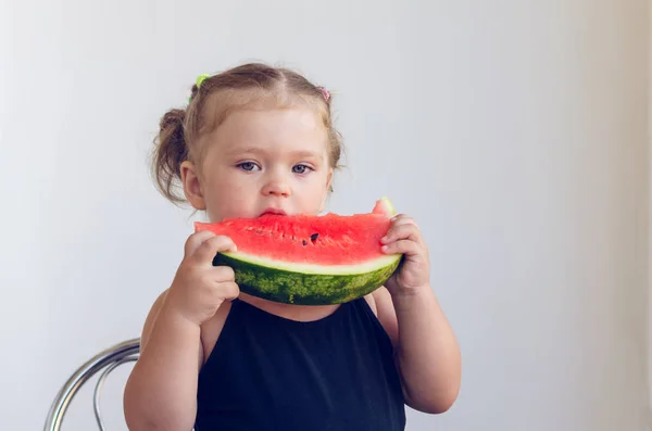 Retrato de una niña comiendo una rebanada de jugosa sandía madura —  Fotos de Stock