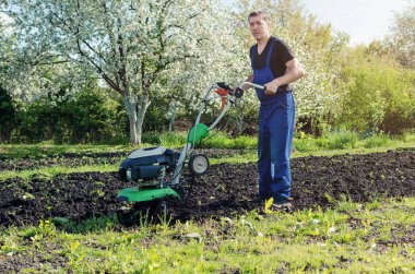 Bahar bahçede tiller makine ile çalışan adam