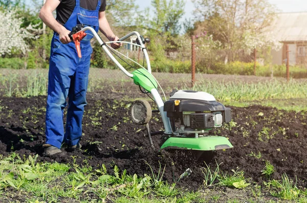 Hombre trabajando en el jardín de primavera con la máquina de timón — Foto de Stock