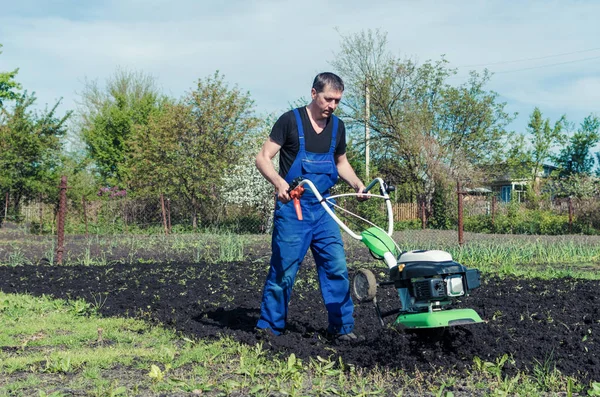 Чоловік працює на весняному саду з машиною для обробки грунту — стокове фото