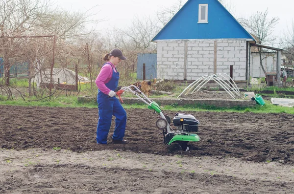 Jovem trabalhando em um jardim de primavera com um cultivador — Fotografia de Stock