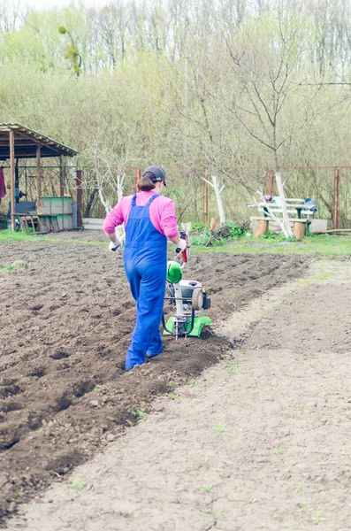 Junges Mädchen bei der Arbeit in einem Frühlingsgarten mit einem Kultivierer — Stockfoto