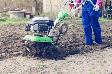 Genç kız bir bahar bahçesinde bir Kültüvatör ile çalışma