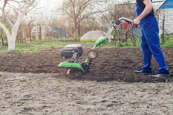 Uomo che lavora nel giardino primaverile con macchina fresatrice — Foto Stock