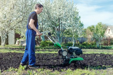 Bahar bahçede tiller makine ile çalışan adam