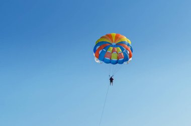 Parasailing ekstrem bir spordur, insanlar mavi gökyüzüne karşı paraşütle uçarlar.