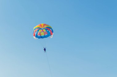 Parasailing ekstrem bir spordur, insanlar mavi gökyüzüne karşı paraşütle uçarlar.