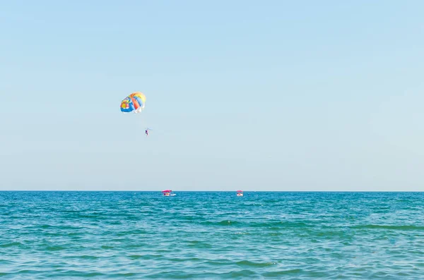 Parasailing is an extreme sport, people fly by parachute against the blue sky — Stock Photo, Image