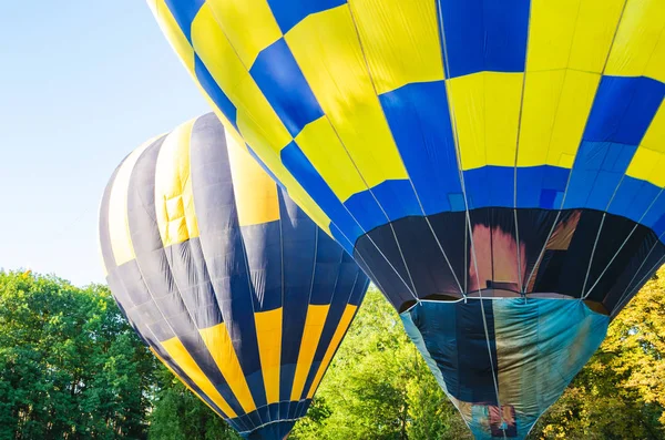 Colorido globo de aire caliente está volando en el cielo azul por encima de los árboles —  Fotos de Stock