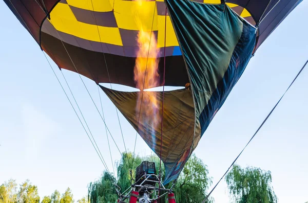 Kleurrijke luchtballon vliegt in de blauwe hemel boven de bomen — Stockfoto