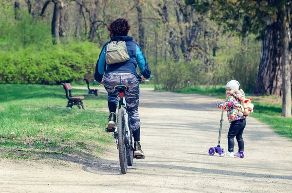 Belaya Tserkov, Ukraine, April 21, 2019 A little girl with a scooter looks at a passing girl on a bicycle