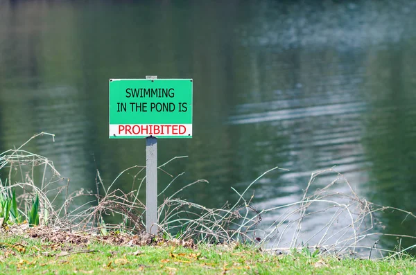 A sign prohibiting swimming in the pond — Stock Photo, Image