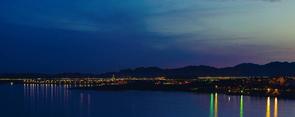 Panorama of night Sharm El Sheikh against the backdrop of the mountains and the reflection of lanterns in the sea