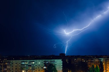 Gece şehri üzerinde şimşek ve gök gürültülü fırtına