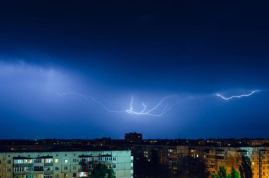 Gece şehri üzerinde şimşek ve gök gürültülü fırtına