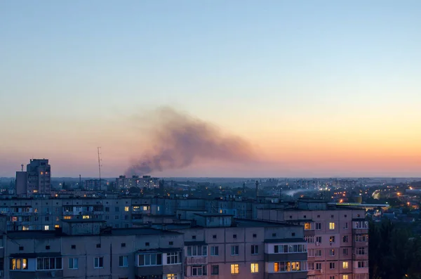Fuego en la ciudad en un edificio de gran altura, humo negro sobre las casas por la noche — Foto de Stock
