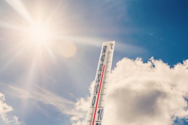 Mavi gökyüzü ve güneşe karşı termometre yüksek sıcaklık gösterir.