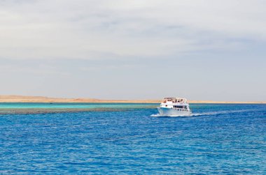 Kızıl Deniz 'in berrak mavi sularında seyahat eden yolcularla turistik bir tekne..