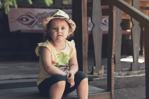 Egy Kalapos Kislány Egy Öreg Faház Verandáján — Stock Fotó