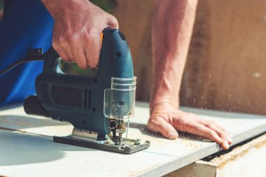 Bir marangoz elektrikli testereyle tahta bir bezi testereyle keser..