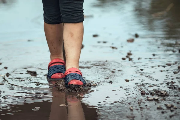 Children\'s feet walking in a muddy puddle after the rain.