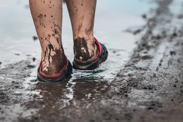 雨后孩子们的脚在泥泞的水坑里走路 — 图库照片