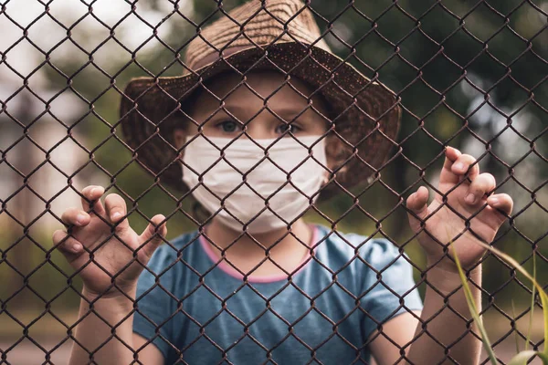 Uma Criança Com Uma Máscara Médica Segura Cerca Com Mãos — Fotografia de Stock
