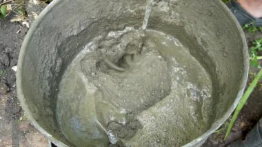 Bir işçi karıştırıcı kullanarak çimento harcı karıştırıyor.