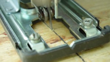 Bir marangoz elektrikli bir yapbozla tahtayı keser.