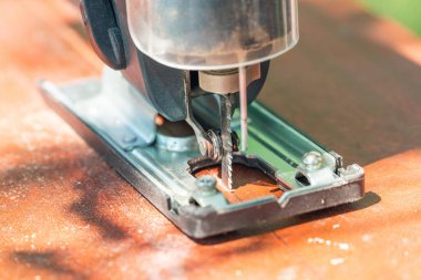 Bir marangoz elektrikli bir yapbozla tahtayı keser..