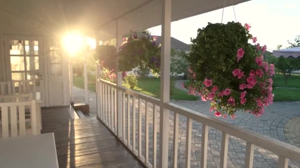 Evin verandası ve güneş ışığı çiçekleri rüzgarda hareket ediyor. — Stok video