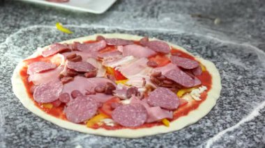 Şef pizza salamı yapıyor ince hamurlu sebze ve sosis