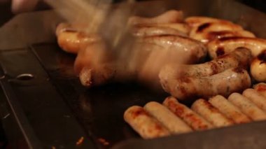 Aşçı sobada kızartılmış sosisler hazırlar organik sosisler sokak yemekleri