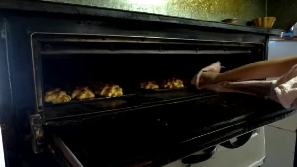 Baker removing tray of baked pastries from oven chef prepares pastries — Stock Video