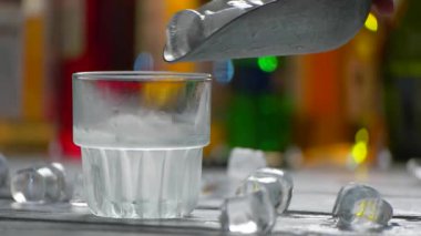 Buz küpleri yavaş yavaş düşüyor. Kepçeler buzu cama koyuyor.