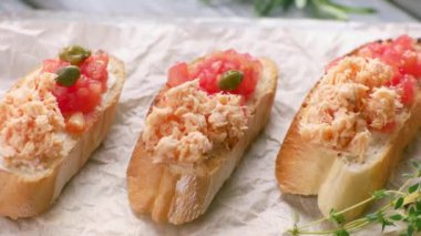 Maşalar sandviçlere kapari koyar. Somonlu balık bruschetta ile baget dilimleri.