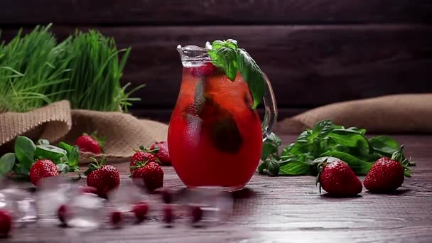 Cruche en verre de limonade fraîcheur aux fraises et canneberges sur fond de bois — Video