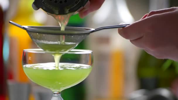 손으로 체에 흐르는 녹색 음료는 음료 위에 체를 올려 놓는다 — 비디오