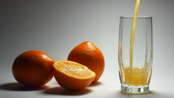 Zumo de naranja bebida se vierte sobre un fondo blanco — Vídeo de stock