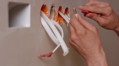 Elektrikçi, elektrik üreten kabloları temizliyor.