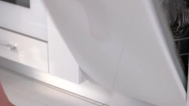 Ev hanımı bulaşık makinesinden temiz tabakları çıkarıyor.