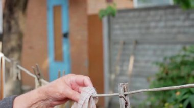 Yaşlı eller çamaşırları bahçeye asar.