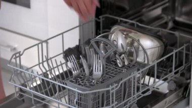 Temiz çatal bıçaklı bulaşık makinası. Kadın elleri bulaşık makinesinden bulaşıkları çıkarıyor.