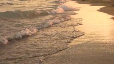 Gün batımında deniz kıyısında küçük dalgalar