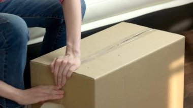 Kadın elleri keçeli kalemle kutu paketliyor.