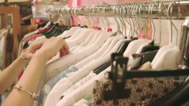 Руки девушки, выбирающей одежду на вешалках продаж — стоковое видео