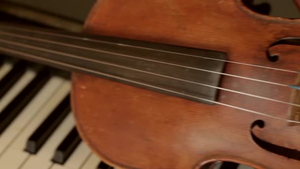 Gammal fiol ligger på piano nycklar stradivarius violin vintage musikinstrument — Stockvideo